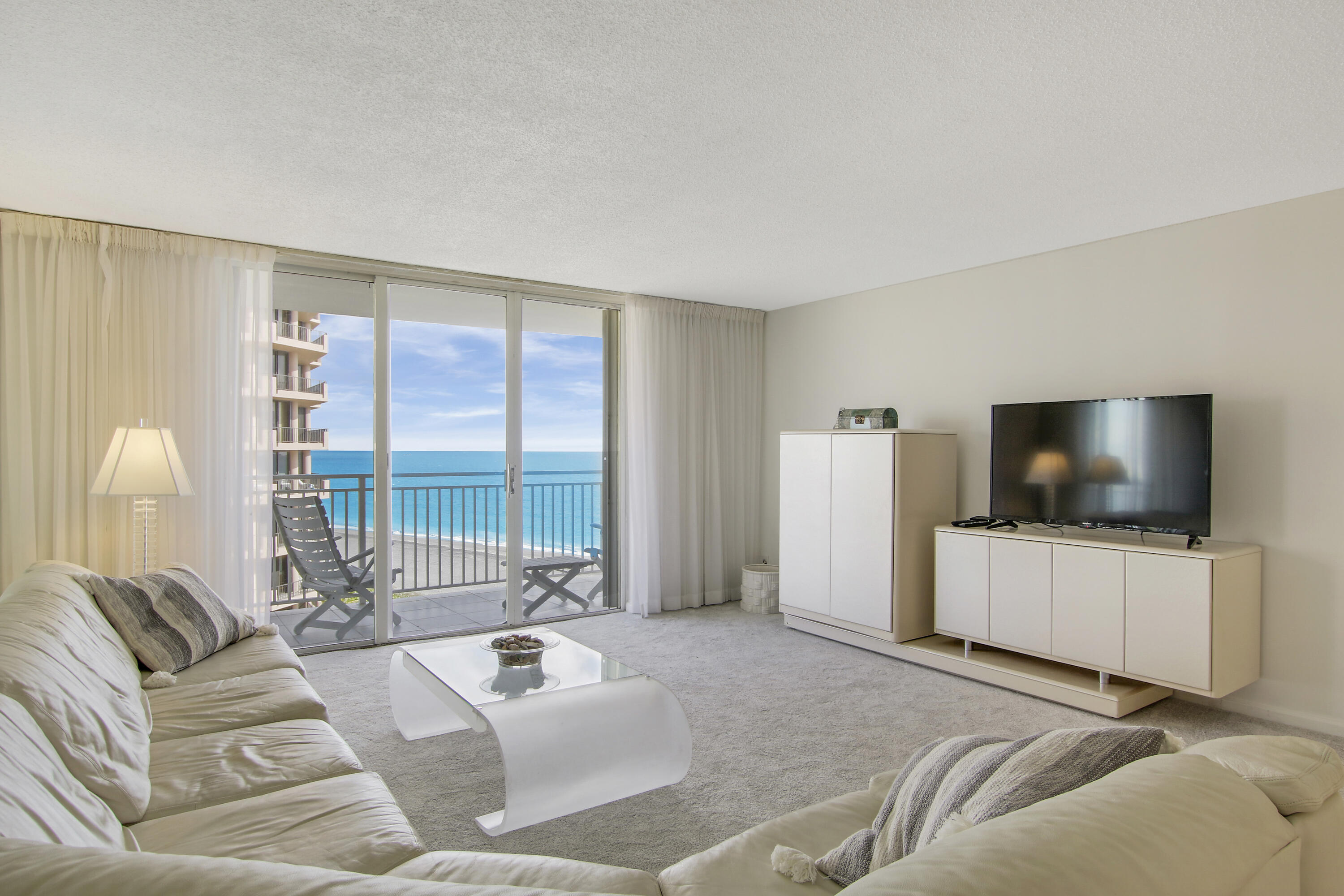 500 Ocean Drive, Unit E9A Juno Beach, FL 33408 - Photo 4 of 21 a living room with furniture and a flat screen tv
