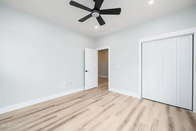 a view of empty room with wooden floor and ceiling fan