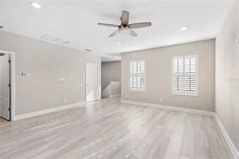 a view of an empty room with a window and wooden floor