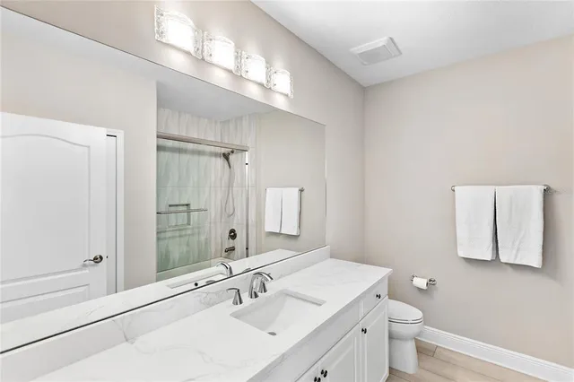 a bathroom with a sink a toilet a large mirror and shower
