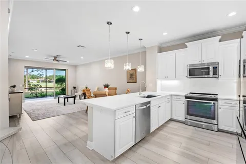 a kitchen with stainless steel appliances kitchen island granite countertop a stove top oven a sink a dining table and chairs