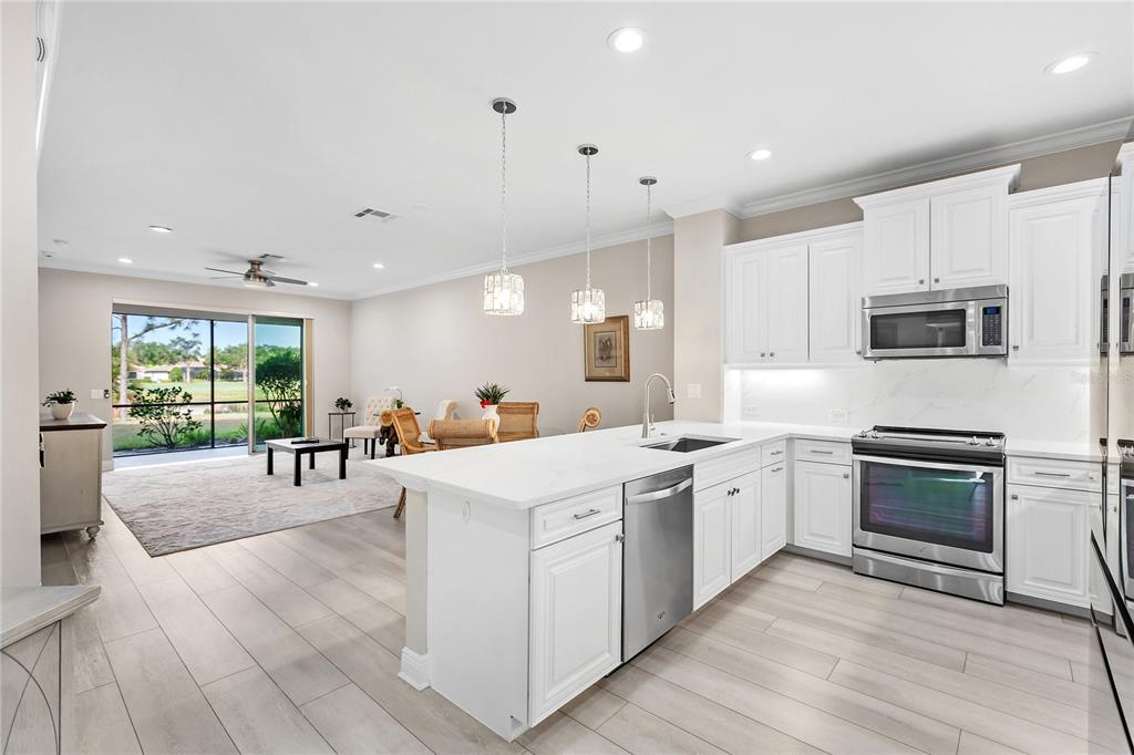 8142 Miramar Way Lakewood Ranch, FL 34202 - Photo 5 of 45 a kitchen with stainless steel appliances kitchen island granite countertop a stove top oven a sink a dining table and chairs