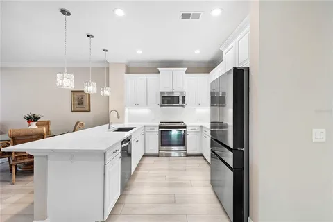 a large kitchen with stainless steel appliances kitchen island granite countertop a refrigerator and a stove top oven