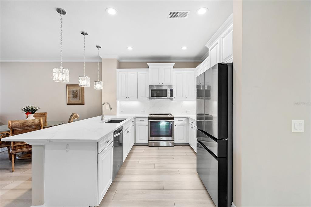 8142 Miramar Way Lakewood Ranch, FL 34202 - Photo 7 of 45 a large kitchen with stainless steel appliances kitchen island granite countertop a refrigerator and a stove top oven