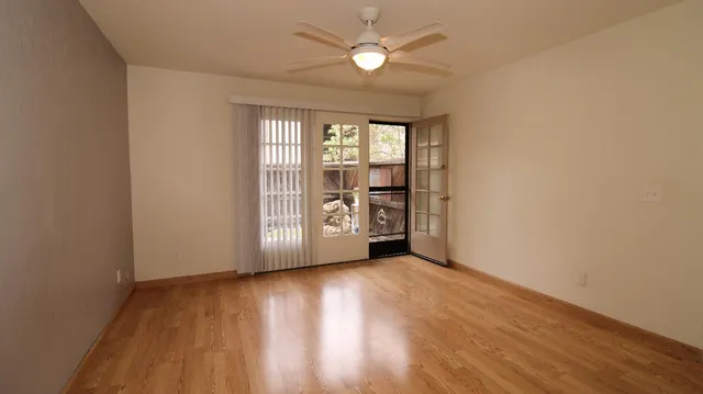 a view of an empty room with a window and wooden floor