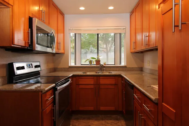 a kitchen with stainless steel appliances granite countertop a sink stove and cabinets