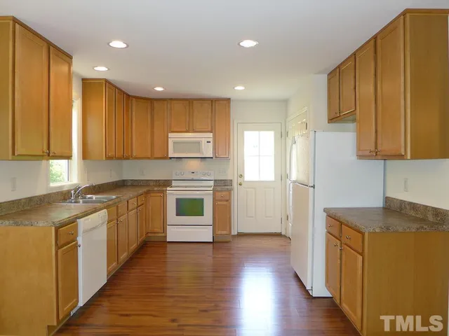 a kitchen with stainless steel appliances granite countertop wooden cabinets a refrigerator a sink a stove and a wooden floors