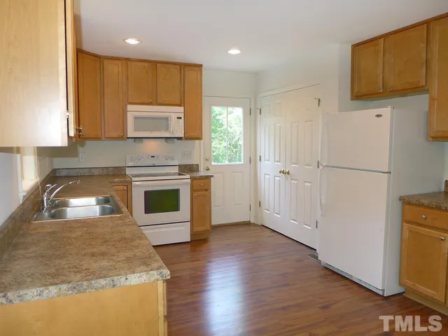 a kitchen with stainless steel appliances granite countertop a refrigerator a stove top oven with a sink and dishwasher