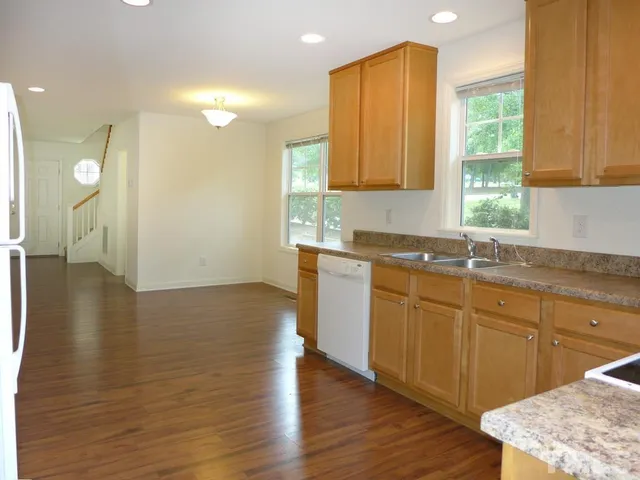a kitchen with stainless steel appliances granite countertop a sink a stove cabinets and wooden floor