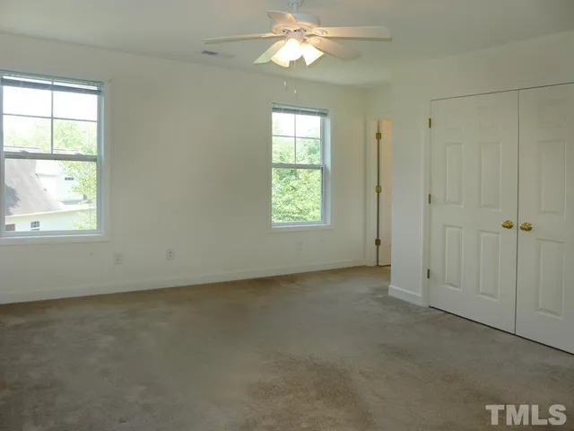 an empty room with a window and a ceiling fan