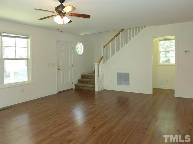 a view of an empty room with a window and wooden floor
