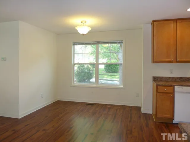 an empty room with wooden floor cabinet and windows