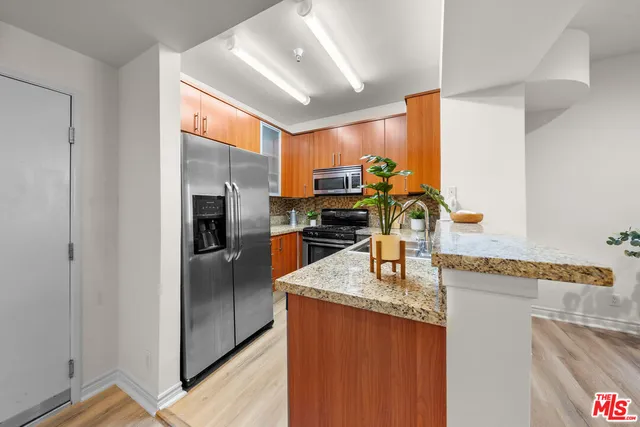 a kitchen with stainless steel appliances granite countertop a refrigerator a sink and a stove
