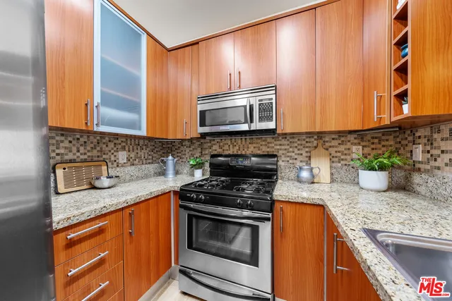 a kitchen with granite countertop stainless steel appliances a stove sink and microwave
