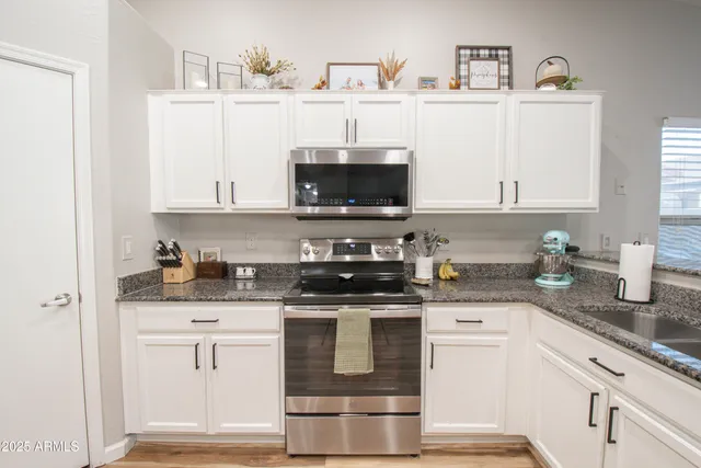 a kitchen with stainless steel appliances granite countertop a stove a sink and a microwave