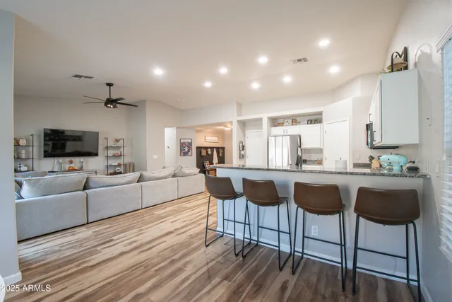 a living room with furniture a flat screen tv and kitchen view