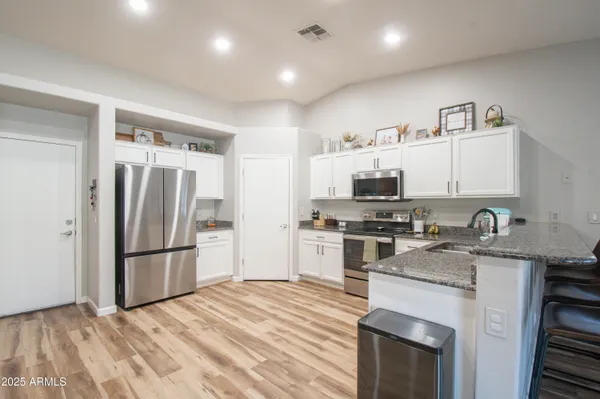 a kitchen with granite countertop a refrigerator stove and sink