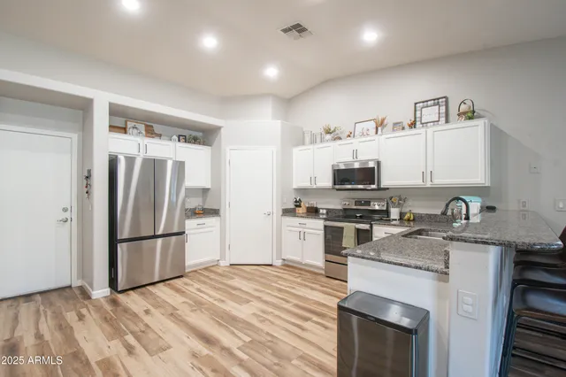a kitchen with granite countertop a refrigerator stove and sink