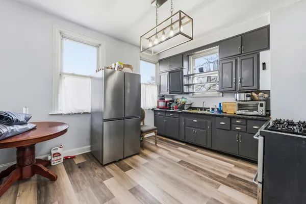 a kitchen with stainless steel appliances granite countertop a refrigerator a sink dishwasher a stove a dining table and chairs with wooden floor