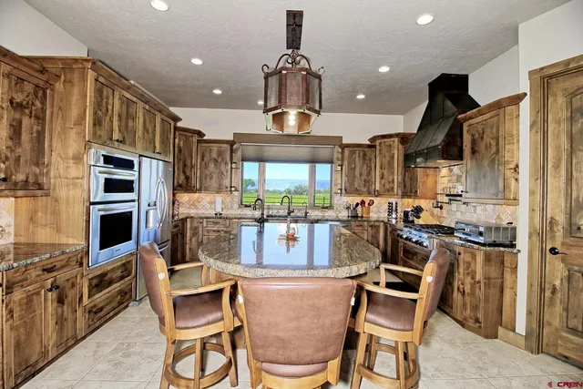 a kitchen with stainless steel appliances kitchen island granite countertop a refrigerator and chairs