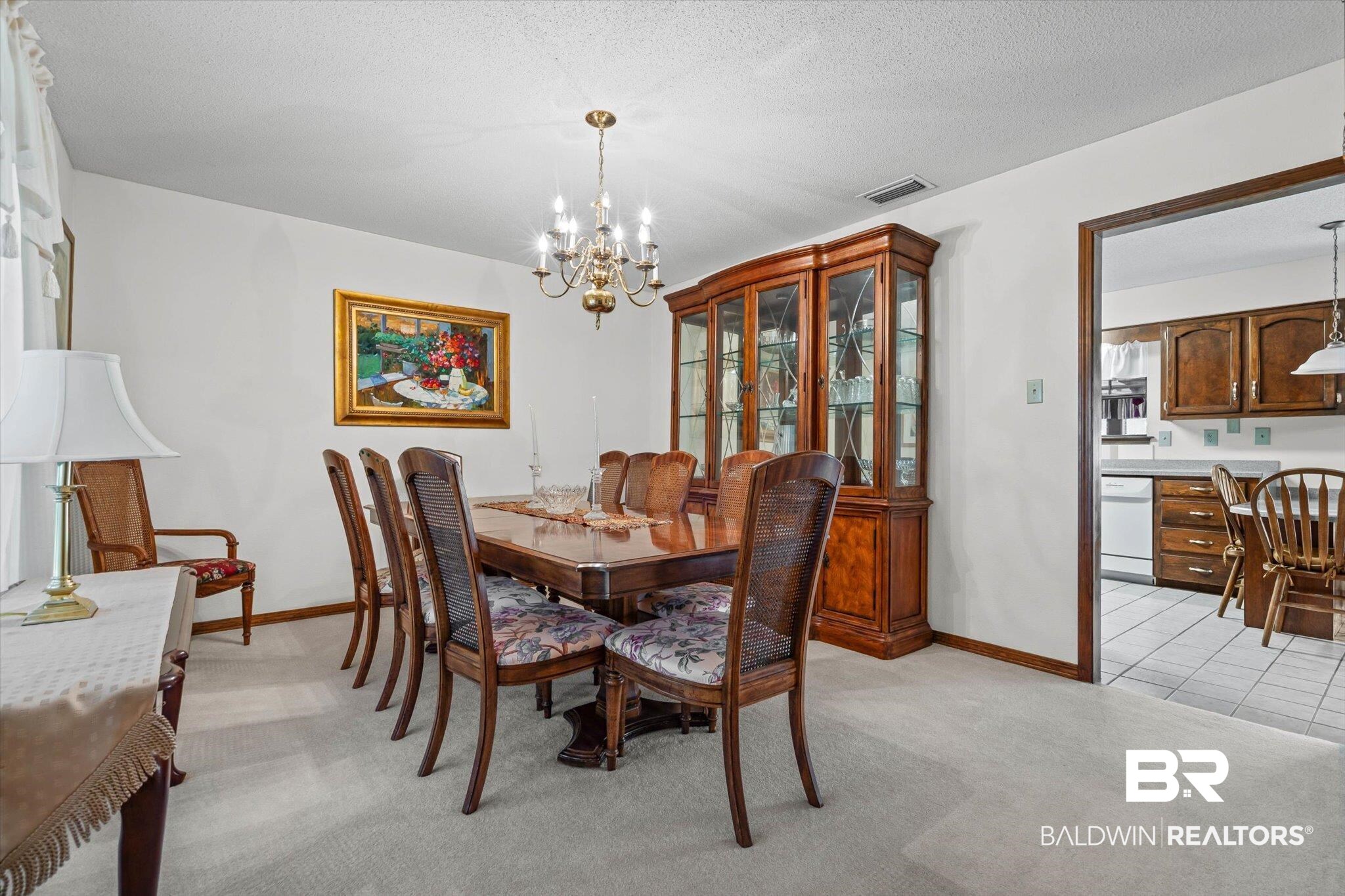 1900 Foxfire Road Mobile, AL 36618 - Photo 5 of 36 Dining area with light carpet, a chandelier, and a textured ceiling