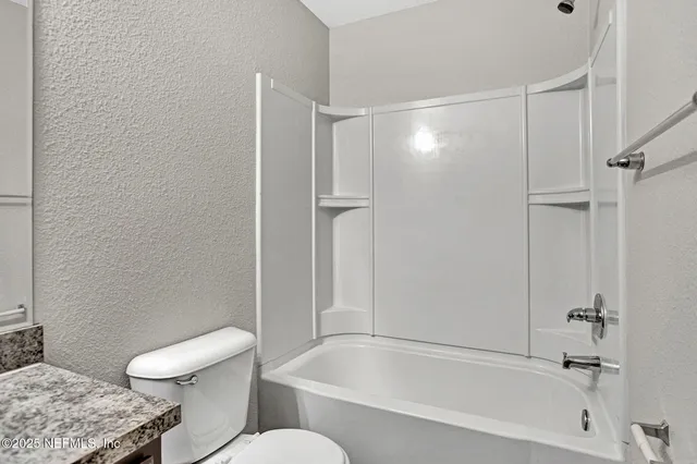 a bathroom with a granite countertop bathtub shower and toilet