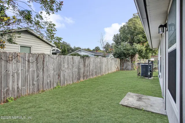 a view of backyard with wooden fence and large trees