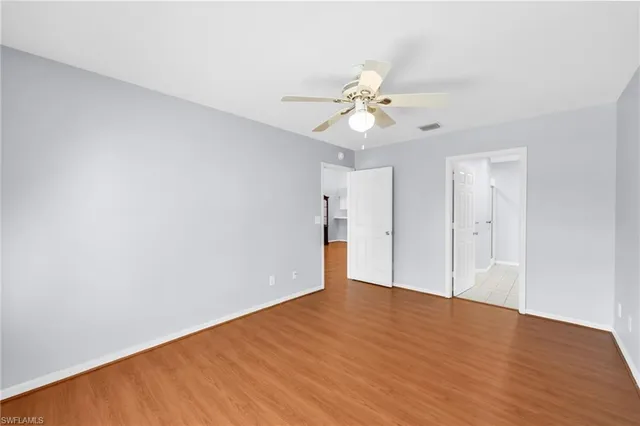 an empty room with a chandelier fan and windows