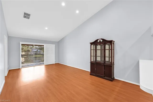 a view of an empty room with wooden floor and window