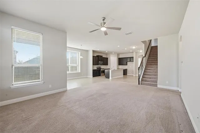 an empty room with a ceiling fan and windows