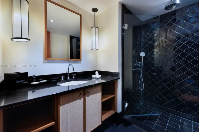 a bathroom with a granite countertop sink a mirror and a shower