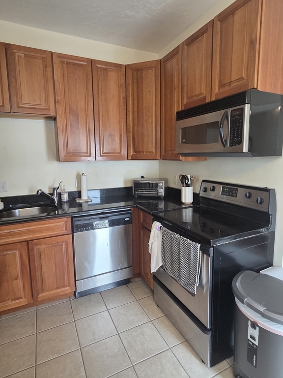 84 South, Unit 84 Waltham, MA 02451 - Photo 3 of 9 a kitchen with stainless steel appliances granite countertop a stove a sink and a microwave