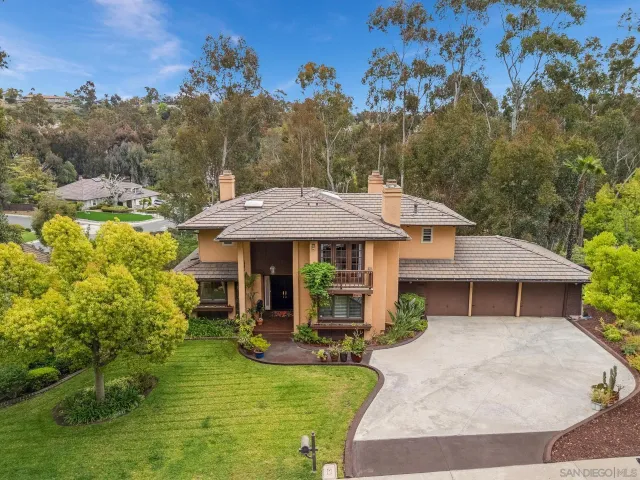 a view of a house with table and chairs under an umbrella