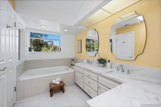 a bathroom with a granite countertop tub a double vanity sink and mirror