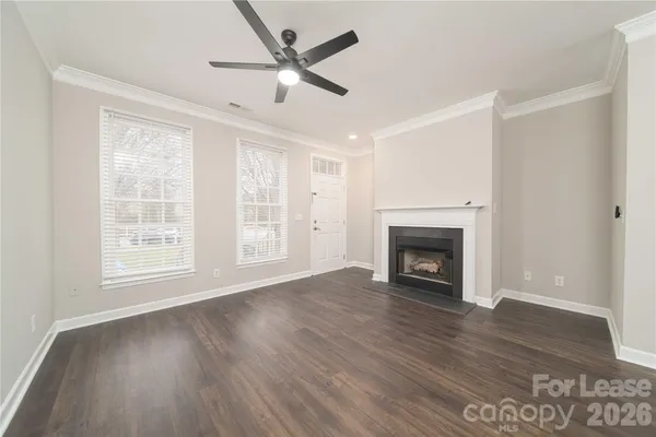 an empty room with wooden floor fireplace and windows