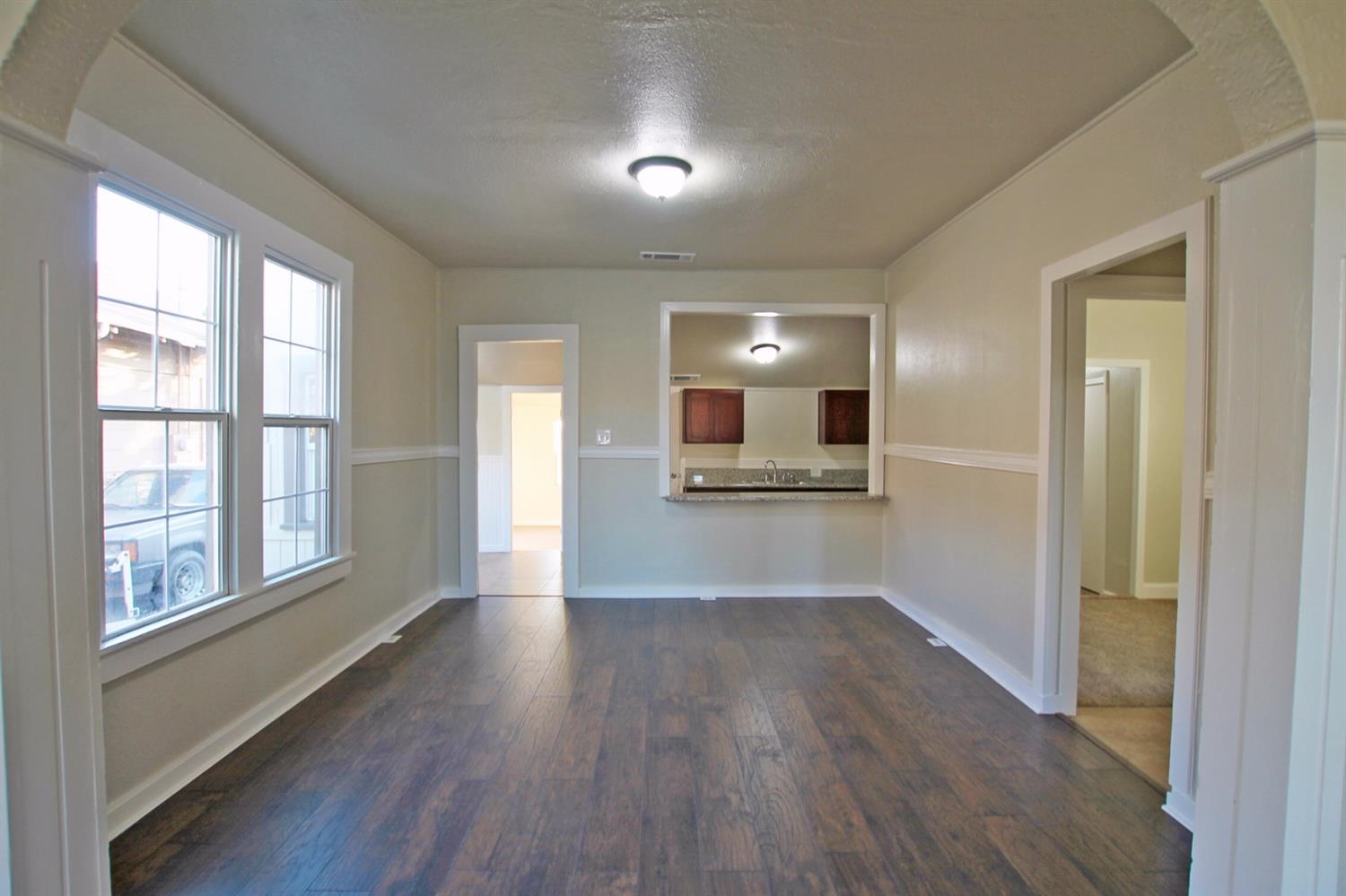 1115 M Street Reedley, CA 93654 - Photo 8 of 10 a view of a kitchen and an empty room with wooden floor and a window