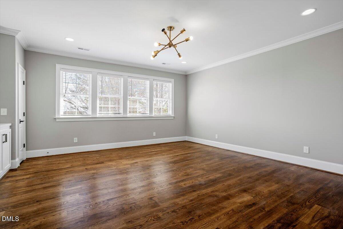 12616 Village Springs Road Raleigh, NC 27614 - Photo 49 of 89 an empty room with wooden floor chandelier and windows