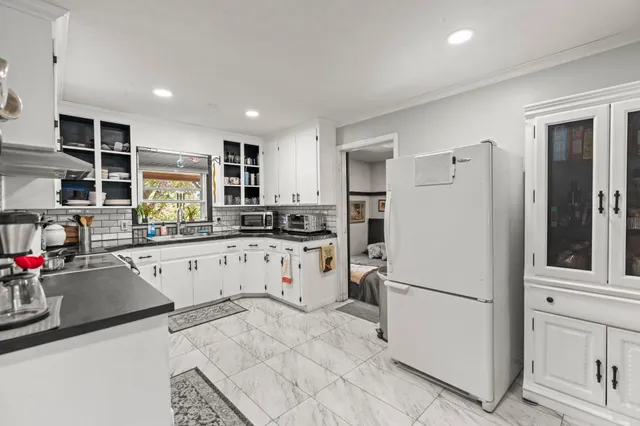a kitchen with refrigerator a sink dishwasher a refrigerator and white cabinets with wooden floor