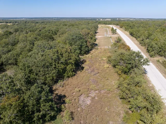 an aerial view of residential houses with outdoor space and trees