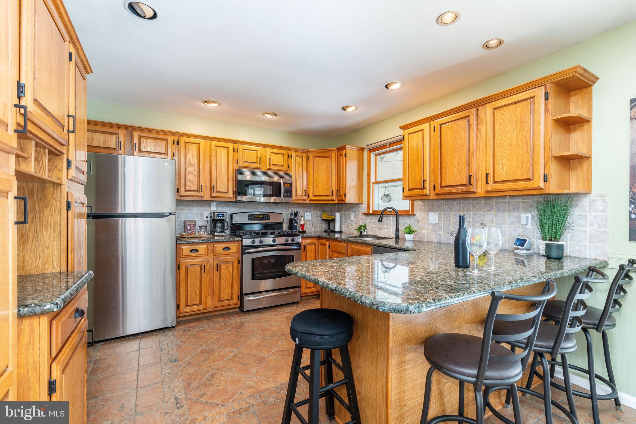 583 Lake Boulevard Lindenwold, NJ 08021 - Photo 12 of 51 a kitchen with stainless steel appliances granite countertop a refrigerator a stove a sink a dining table and chairs with wooden floor