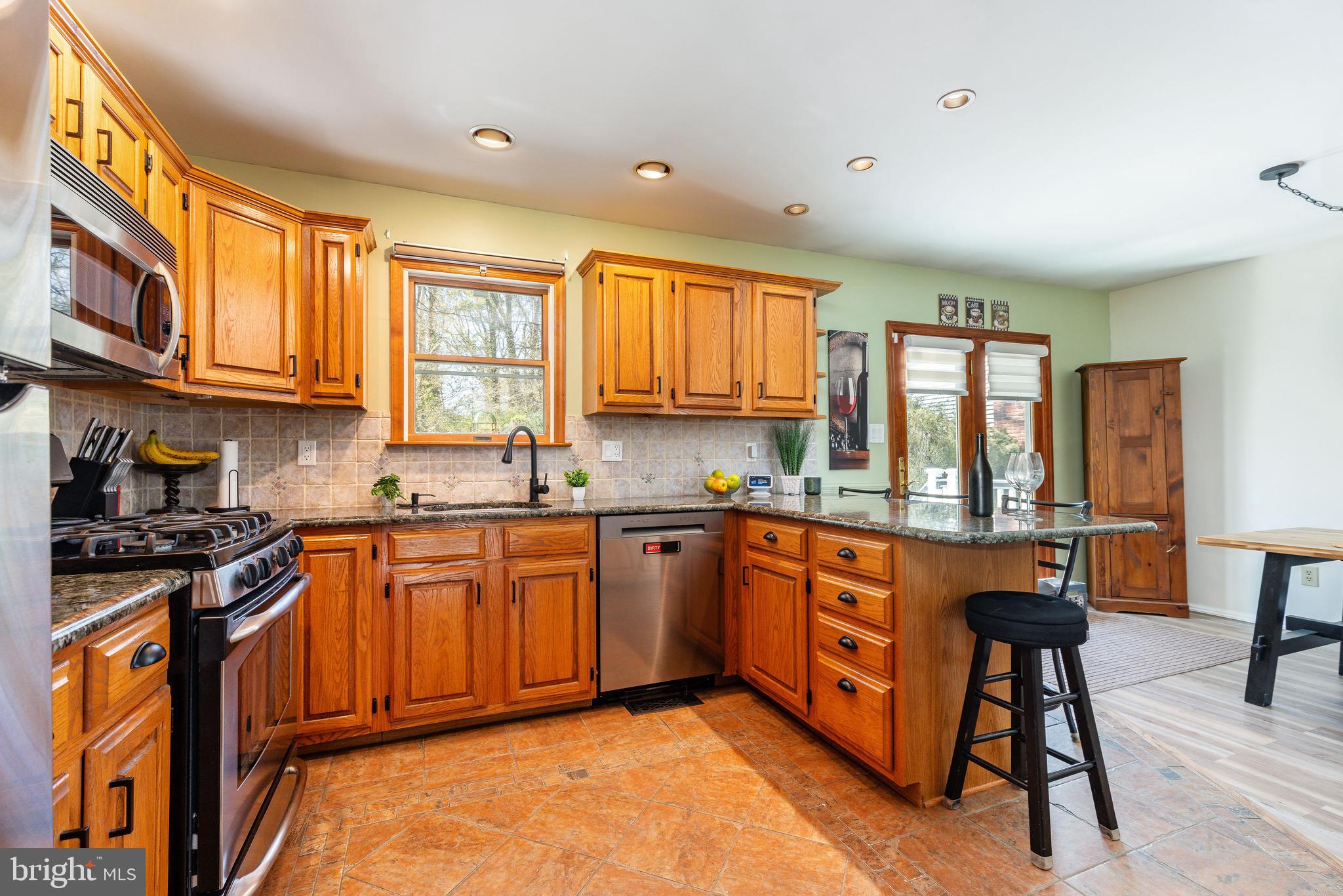 583 Lake Boulevard Lindenwold, NJ 08021 - Photo 15 of 51 a kitchen with stainless steel appliances granite countertop wooden cabinets a stove a sink a dining table and chairs