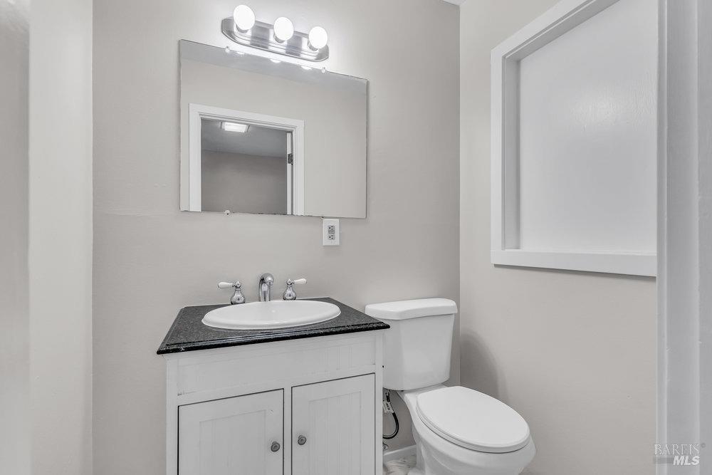 4785 Highway 12 Santa Rosa, CA 95409 - Photo 39 of 80 a bathroom with a granite countertop sink a toilet and a mirror