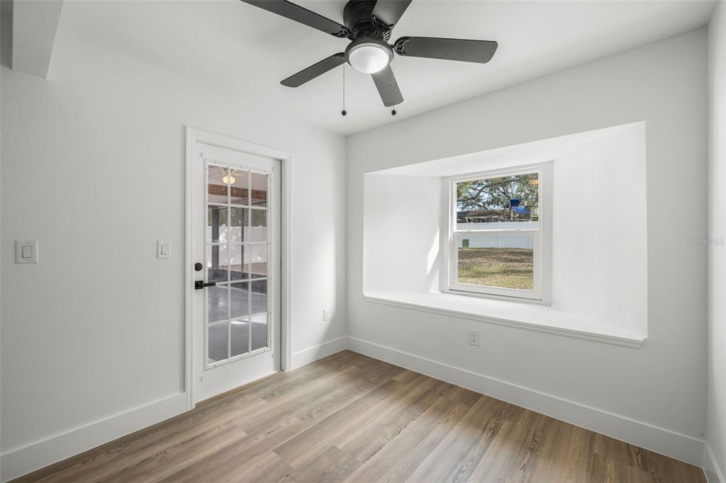 8082 Pagoda Drive Spring Hill, FL 34606 - Photo 18 of 28 an empty room with wooden floor chandelier fan and windows