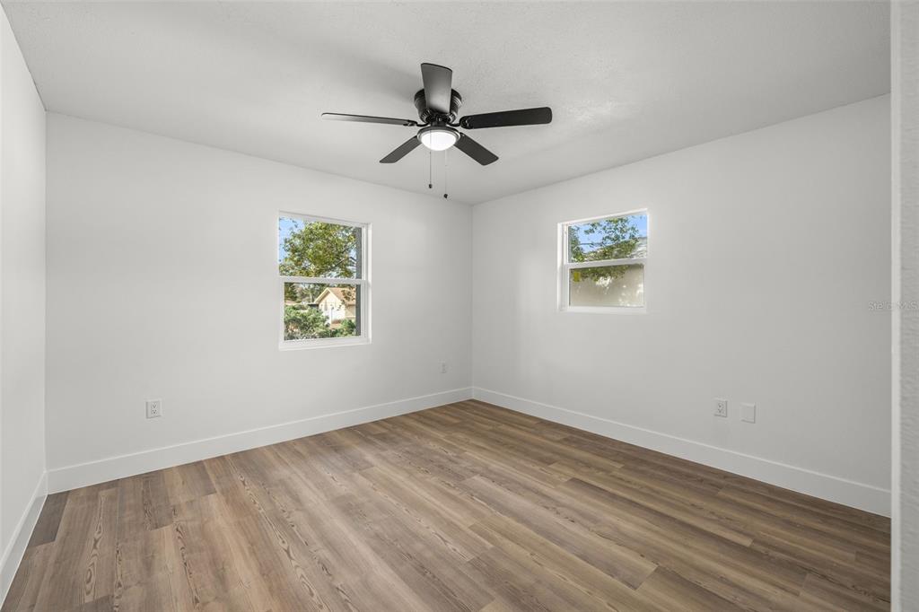 8082 Pagoda Drive Spring Hill, FL 34606 - Photo 20 of 28 an empty room with wooden floor ceiling fan and windows