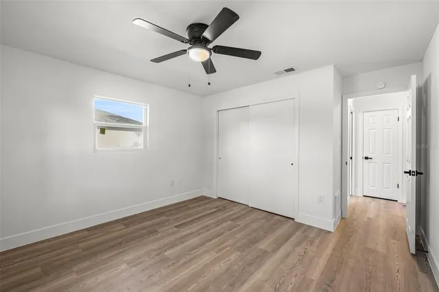an empty room with wooden floor and a ceiling fan