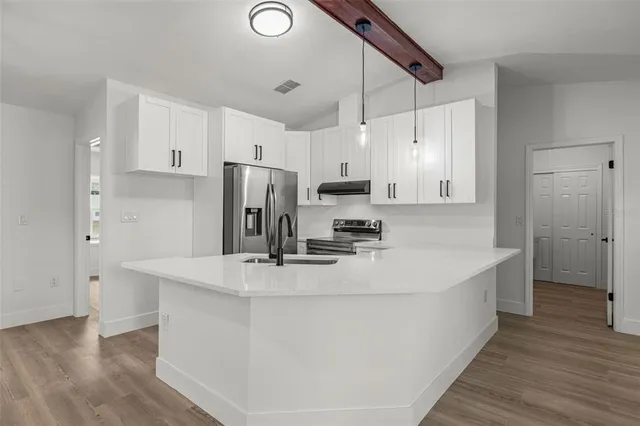 a kitchen with kitchen island a white counter top space cabinets and stainless steel appliances