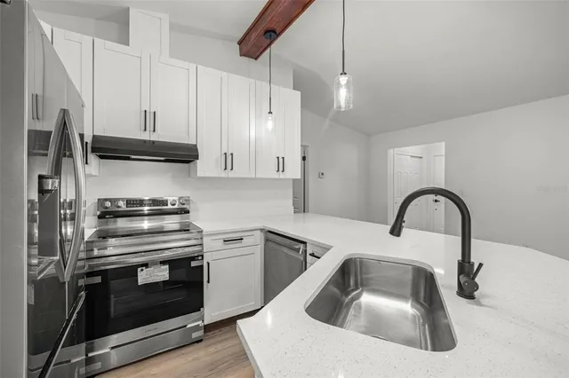 a kitchen with granite countertop a sink stainless steel appliances and cabinets