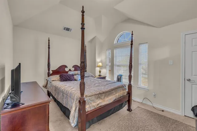 a bedroom with a bed and a flat tv screen on the wall