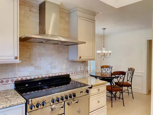 a kitchen with stainless steel appliances granite countertop a stove a sink and white cabinets