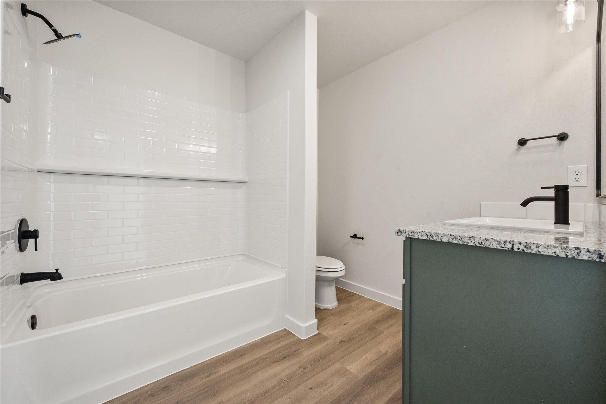 7215 8th Street Lubbock, TX 79416 - Photo 15 of 21 a bathroom with a bathtub a sink a toilet and a shower